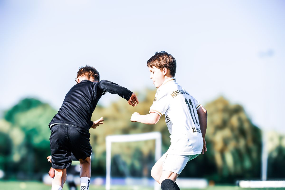 Zwei Jungen duellieren sich auf dem Platz um den Ball